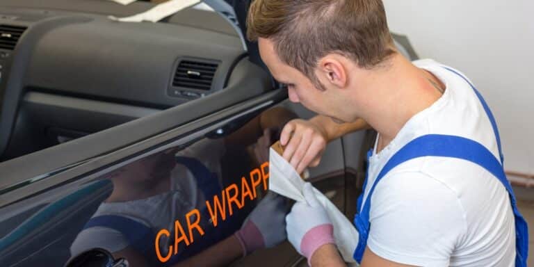 person putting wrap on a dark car