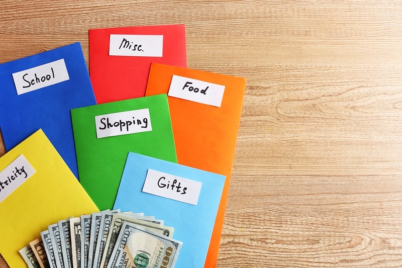 Colourful envelopes with money for needs on wooden background