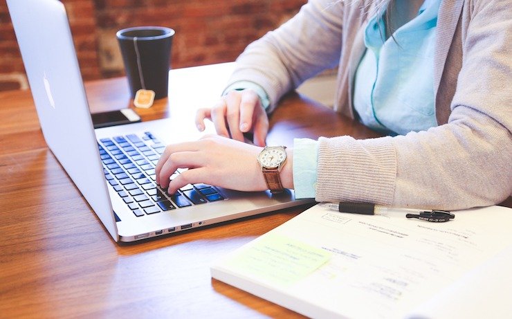 Woman wearing a leather watch with tea nearby using her laptop