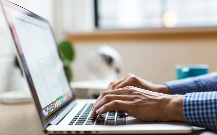 Person typing on a computer with their blue checkered cuffs showing