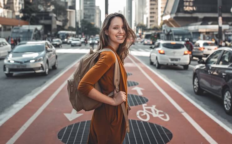 Woman excited about traveling in a city holding a backpack