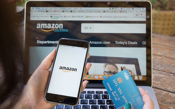 Woman looking at amazon on her phone and laptop while holding her credit card